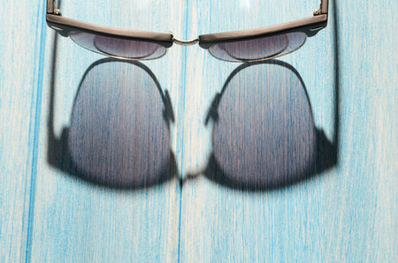 stylish sunglasses on blue wooden table with sunlightの写真素材