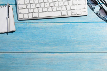 white modern keyboard with notepad on blue wooden tableの写真素材