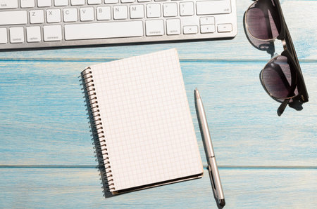 white modern keyboard with notepad on blue wooden tableの写真素材