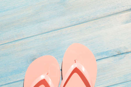 pink flip flops on blue wooden table with sunlightの写真素材