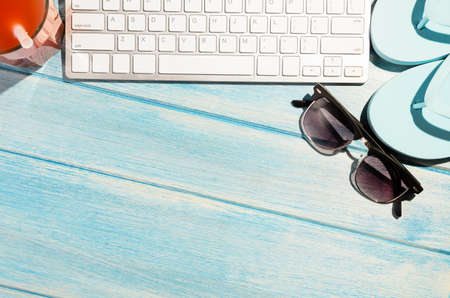 white modern keyboard with beach accessories on blue wooden tableの写真素材