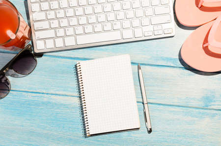 white modern keyboard with beach accessories on blue wooden tableの写真素材