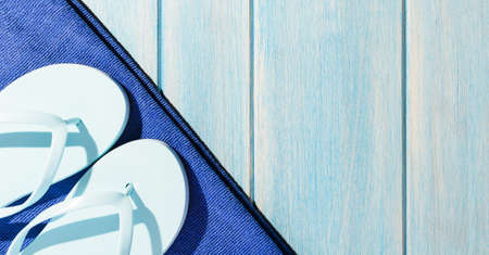 beach accessories. stylish sunglasses with towel and flip flops on blue wooden tableの写真素材