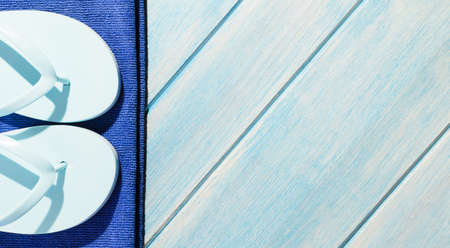 beach accessories. stylish sunglasses with towel and flip flops on blue wooden tableの写真素材