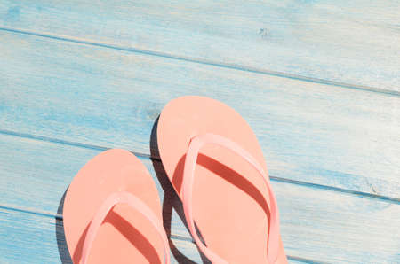 pink flip flops on blue wooden table with sunlightの写真素材