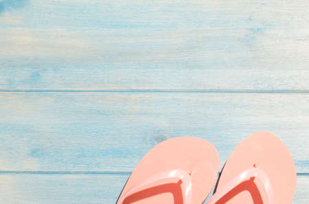 pink flip flops on blue wooden table with sunlightの写真素材