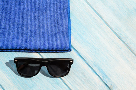 beach accessories. stylish sunglasses with towel on blue wooden table