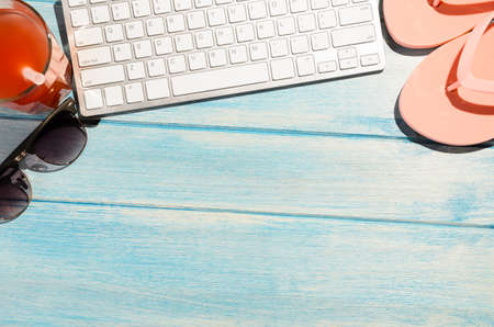 white modern keyboard with beach accessories on blue wooden tableの写真素材