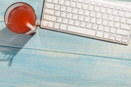 white modern keyboard with beach accessories on blue wooden table