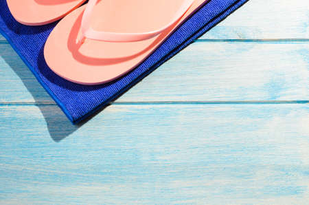 beach accessories. stylish towel and flip flops on blue wooden tableの写真素材