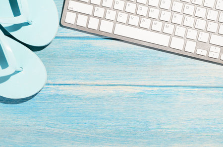 white modern keyboard with beach accessories on blue wooden tableの写真素材