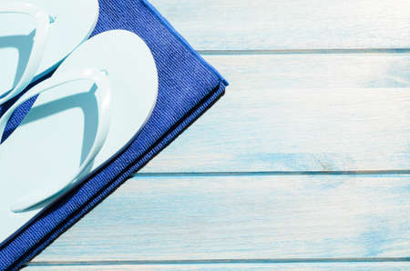 beach accessories. stylish sunglasses with towel and flip flops on blue wooden tableの写真素材