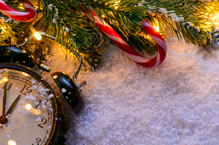 Christmas fir tree with lights and clock on snow in dark, view from above
