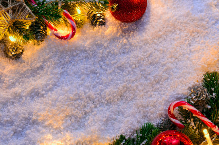 Christmas fir tree with lights and candy cane on snow in dark, view from above