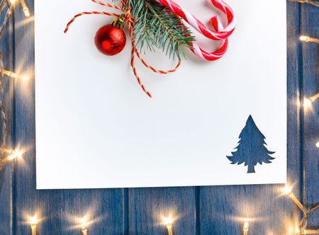 Cut paper in fir-tree shape with decorative lights for christmas card or new year background on blue wooden tableの写真素材