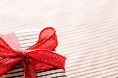 Handmade gift box wrapped with craft paper and red bowの写真素材