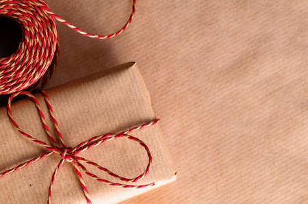 Handmade gift box wrapped with craft paper and red bowの写真素材