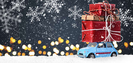 Blue retro toy car delivering Christmas or New Year gifts on festive gray backgroundの写真素材