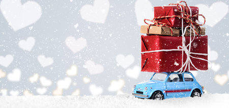 Blue retro toy car delivering heart for Valentine's day on gray backgroundの写真素材