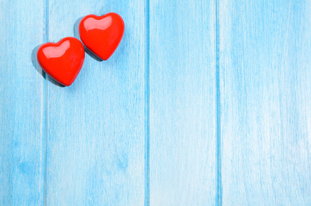Couple of glossy red hearts for Valentines day on blue wooden table