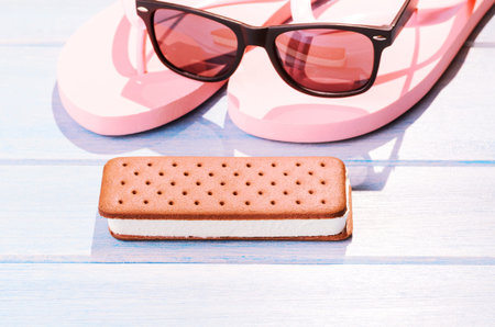 Ice cream sandwich with retro sunglasses on blue table outdoorsの写真素材