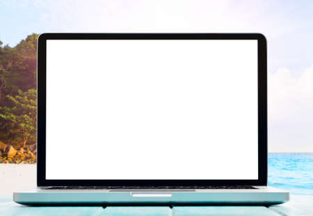 Modern laptop on blue wooden table with blank screen at tropical beachの写真素材