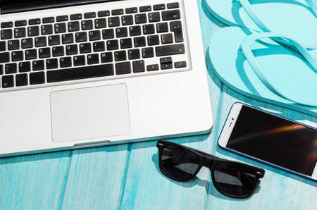 Work on the go. Modern laptop computer with smartphone and sunglasses on blue table, view from aboveの写真素材