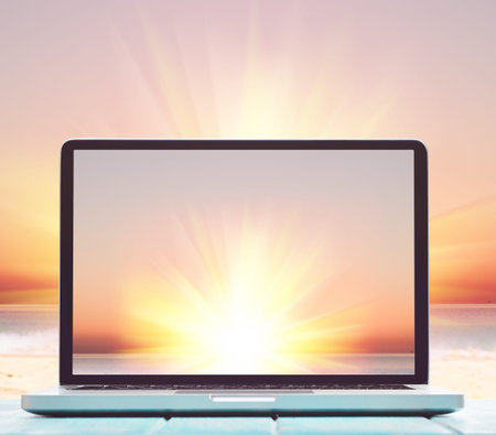 Modern laptop on blue wooden table with blank screen at tropical beachの写真素材