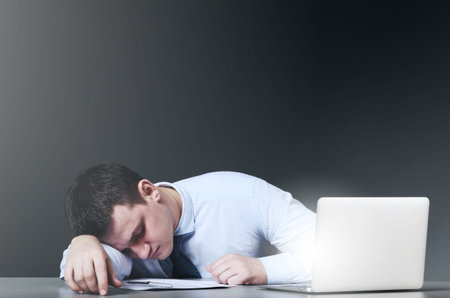 Tired business man is sleeping at his table with laptop
