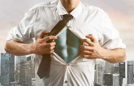 Business superhero. Young businessman showing super hero suit under his shirt down town on sunset.の写真素材