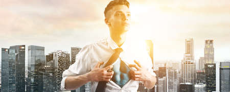 Business superhero. Young businessman showing super hero suit under his shirt down town on sunset.の写真素材
