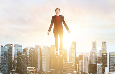 Businessman hovering over down town on sunset.の写真素材