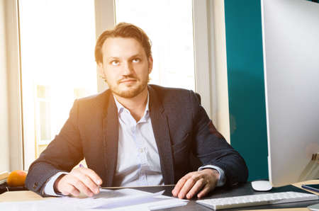 Businessman working computer in modern loft office at sunsetの写真素材