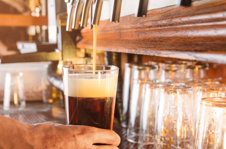 Bartender hand pouring draught beer to glass from a pub tap