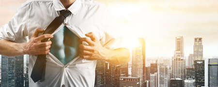 Business superhero. Young businessman showing super hero suit under his shirt down town on sunset.の写真素材