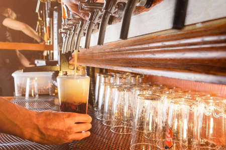 Bartender hand pouring draught beer to glass from a pub tapの写真素材