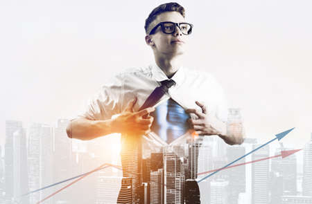 Business superhero double exposure concept. Young businessman showing super hero suit under his shirtの写真素材
