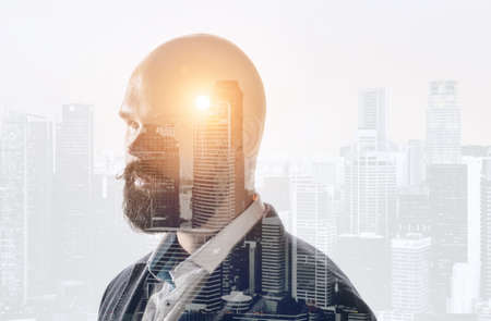 Business idea double exposure concept. Businessman illuminated head mixed with sunset city skylineの写真素材