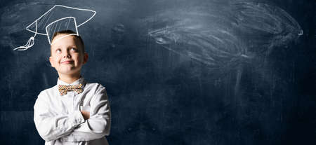 School boy standing against blackboardの写真素材