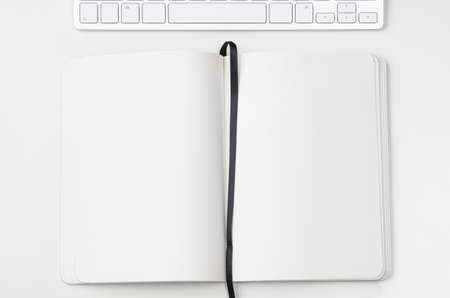 White workplace with keyboard and notebook, view from aboveの写真素材