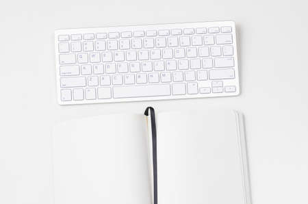 White workplace with keyboard and notebook, view from aboveの写真素材