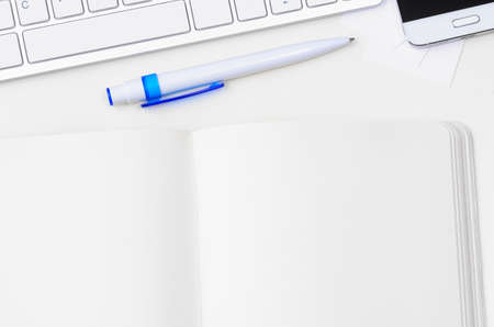 White workplace with keyboard, smartphone and notebook, view from aboveの写真素材