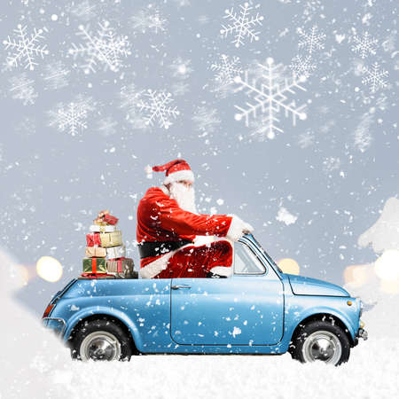 Santa Claus on car delivering Christmas or New Year gifts at snowy gray backgroundの写真素材