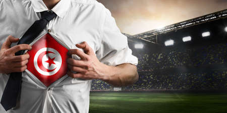 Tunisia soccer or football supporter showing flag under his business shirt on stadium.の写真素材