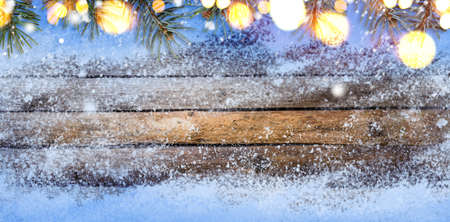 Christmas or New Year snowy seasonal wooden table with fir tree backgroundの写真素材