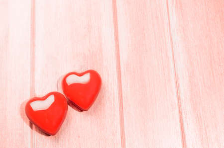 Couple of glossy red hearts for Valentines day on living coral colored wooden tableの写真素材
