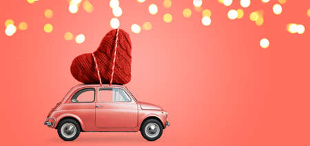 Living coral retro toy car delivering craft heart for Valentines day on coral backgroundの写真素材