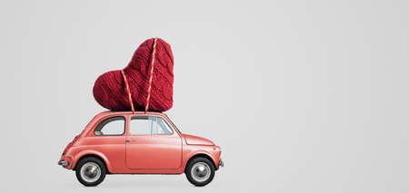 Living coral retro toy car delivering craft heart for Valentines day on gray backgroundの写真素材