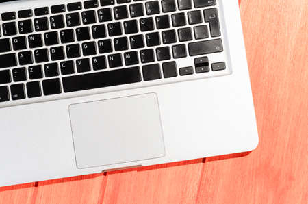 Laptop on living coral colored wooden table on a sunny day, view from aboveの写真素材