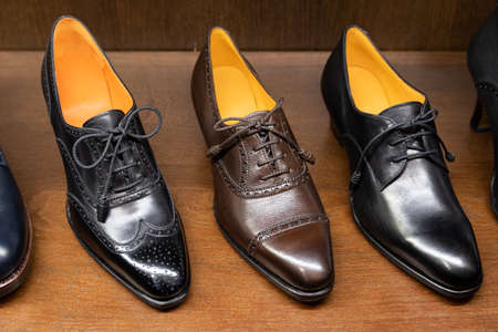 Black and brown full grain leather shoes on wooden display in in men shoes boutique store.の写真素材